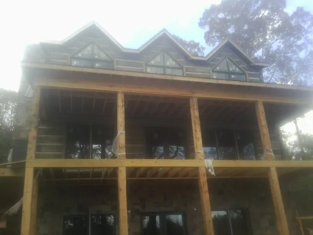 Dormers and porch framing on a large log home under construction — Roof Coating work by our crew in Mannington