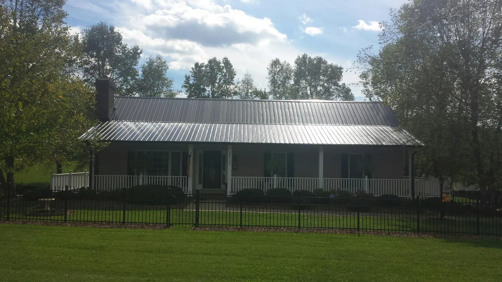 Gray metal roof on a brick ranch with a full width front porch — Gutter Guard Installation work by our crew in Mannington