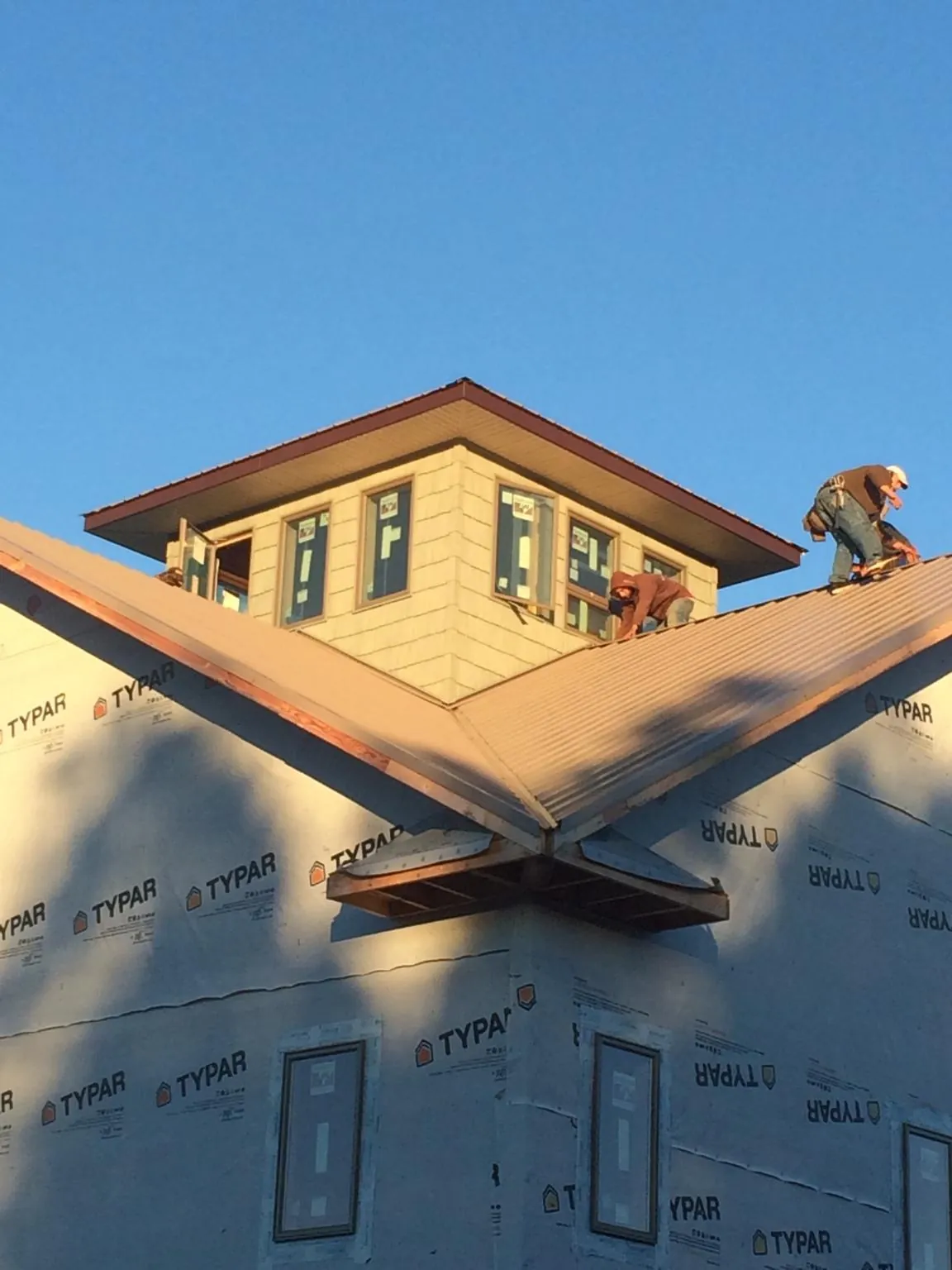Roofers working around a rooftop cupola on a new metal roof at sunset — Roof Waterproofing in Mannington by Roofing Brothers